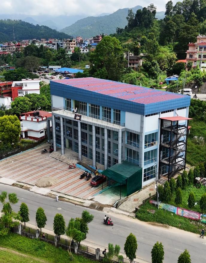 Aerial view of A.K. Complex beside the road in Kamalamai, with hills behind the building